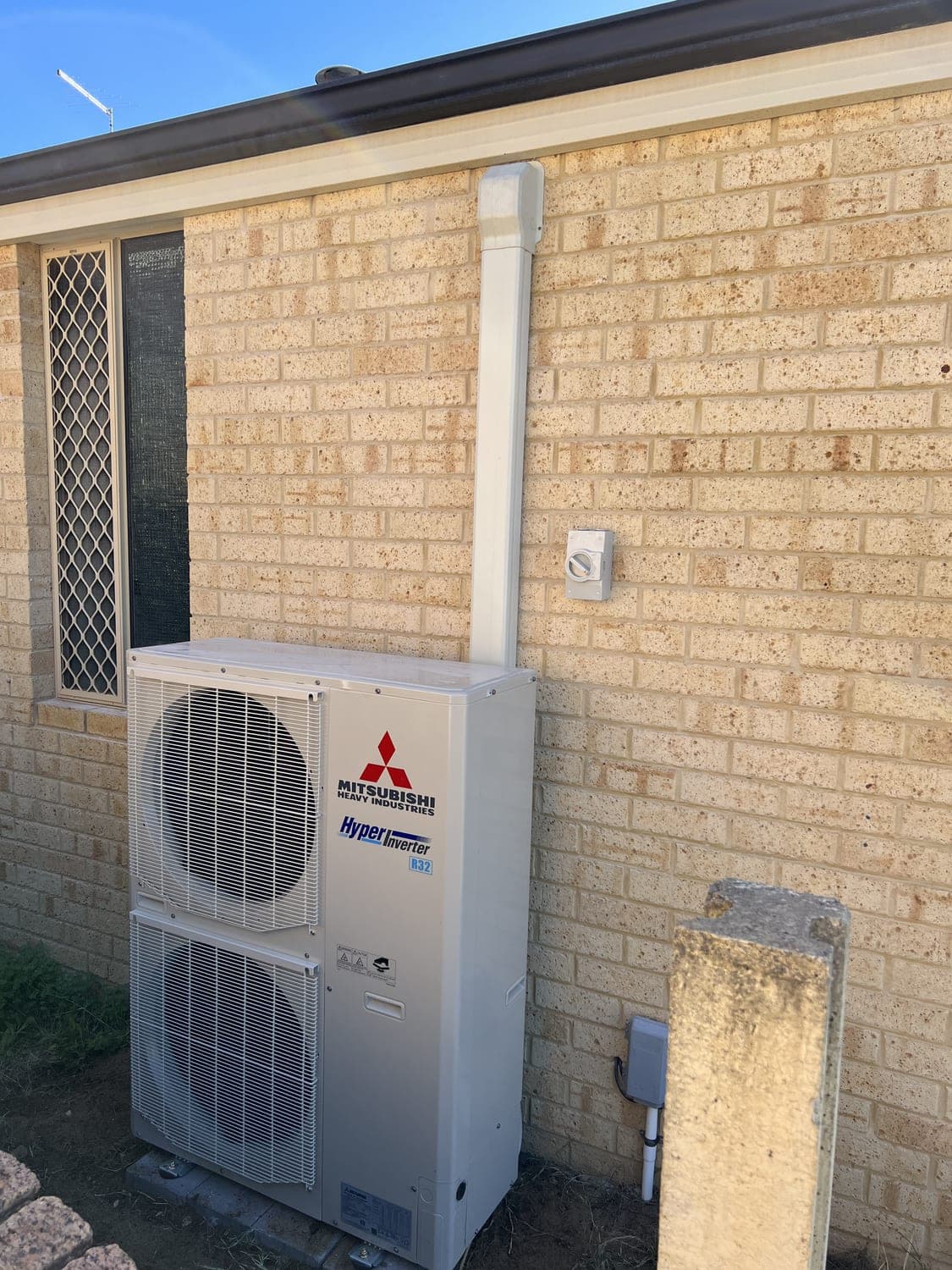 A split-system air conditioner neatly supplied and installed against a brick wall by Brady Electrical.