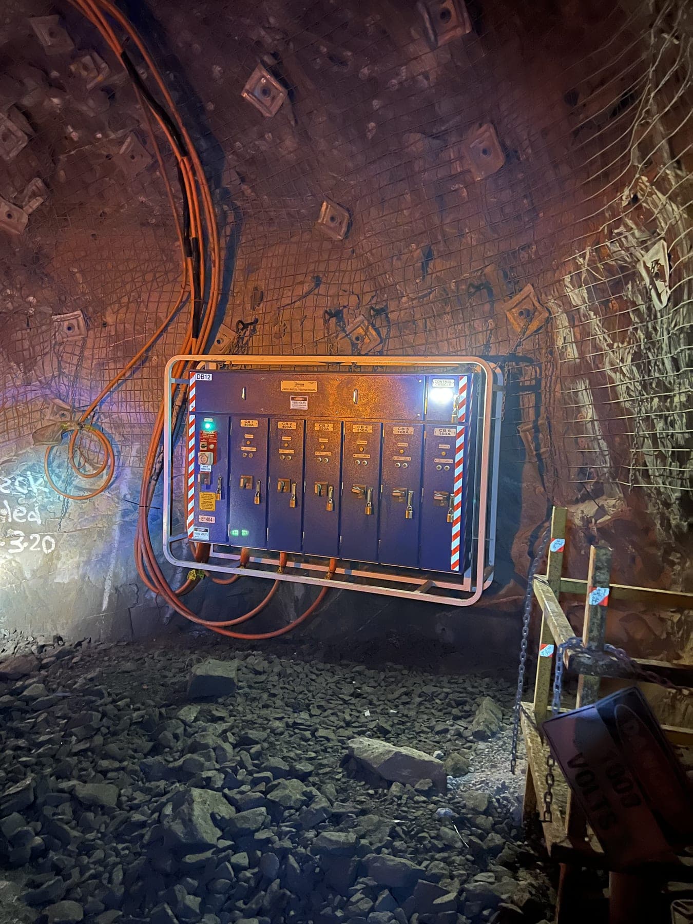 A Brady-installed electrical control panel mounted on a bolted mesh wall in an underground mine tunnel.